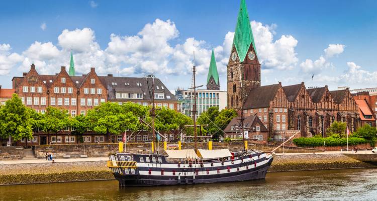 Historische gebouwen en boot langs een rivier.