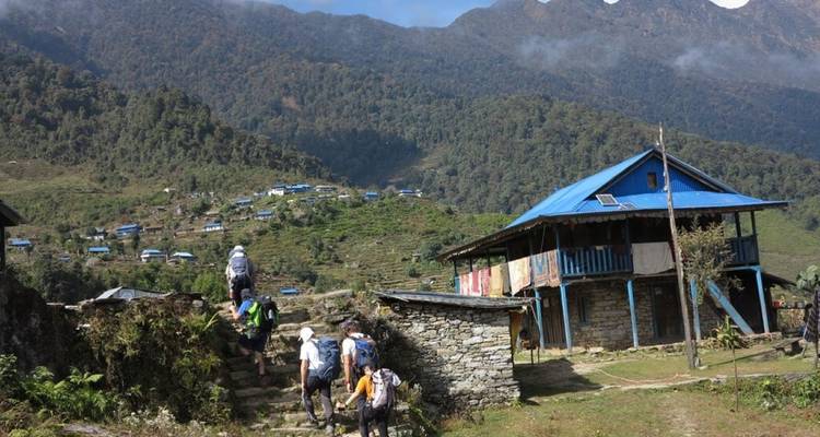 Mensen die trekken in een bergdorp met traditionele huizen met blauwe daken.