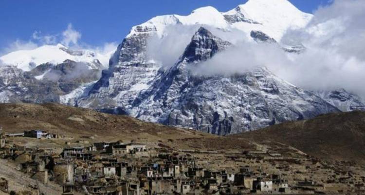 Bergdorf mit großen schneebedeckten Gipfeln im Hintergrund.
