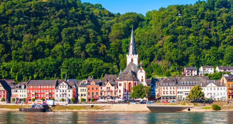 Village pittoresque avec église et maisons colorées au bord d'une rivière.