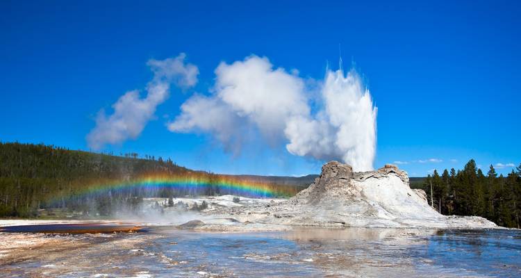 Geyser erupting with a rainbow in the background.