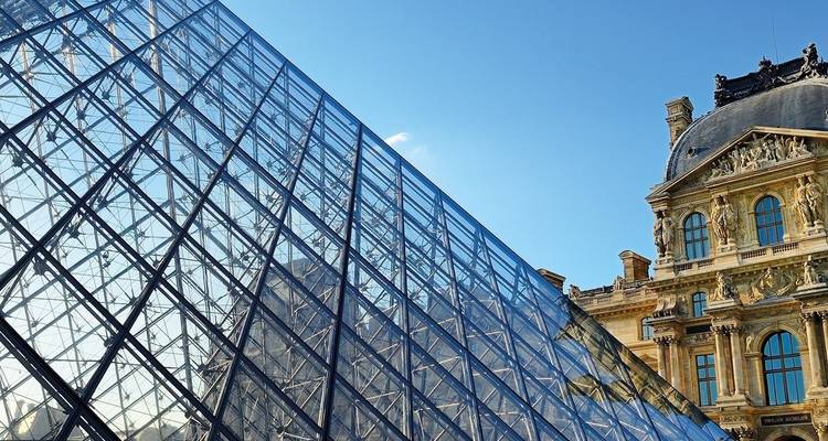 De Louvre Piramide in Parijs met blauwe luchten.