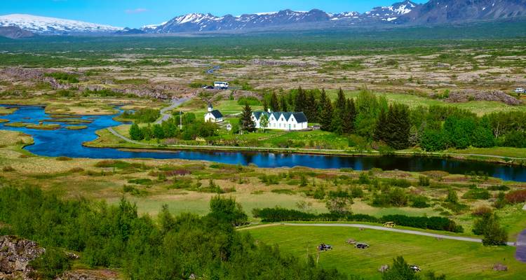 Vue pittoresque du parc national de Thingvellir avec des champs verts et un ciel bleu.