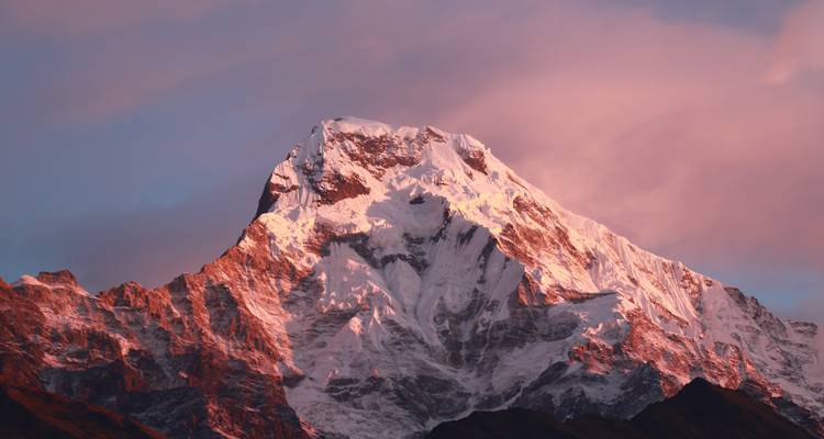 Majestieke met sneeuw bedekte bergpiek verlicht door zonsopgang.