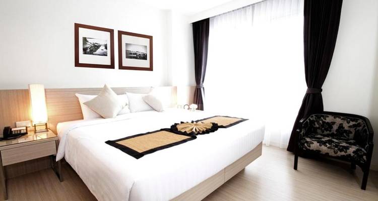 Helles Hotelzimmer mit einem großen Bett und minimalistischer Einrichtung.