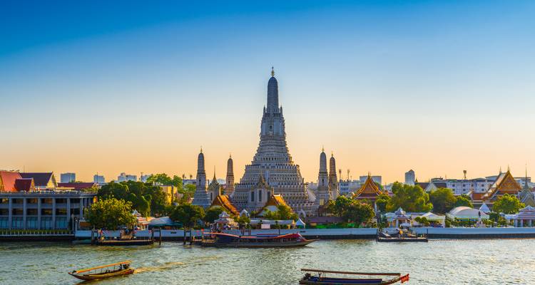 View of Wat Arun temple by the riverside with boats.