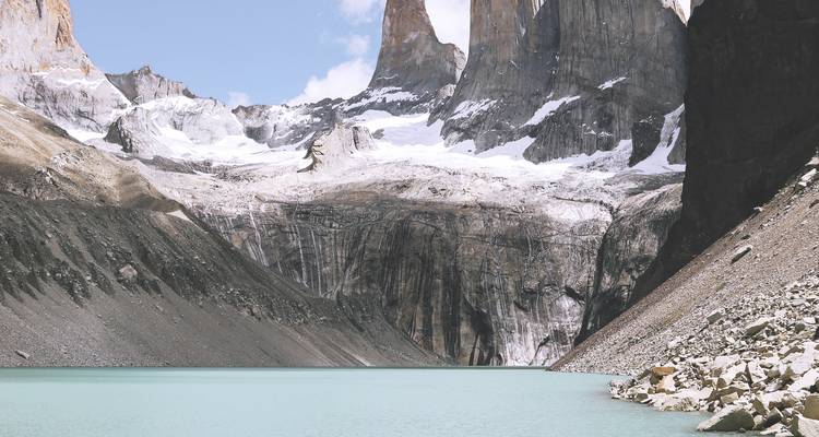 Vue rapprochée d'un lagon bleu laiteux sous des tours de granit striées de neige en Patagonie.