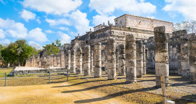 Ruines antiques avec des colonnes de pierre sous un ciel bleu éclatant.