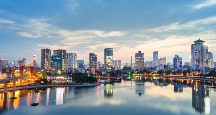 Stadtskyline bei Abenddämmerung mit Spiegelungen auf dem Wasser.
