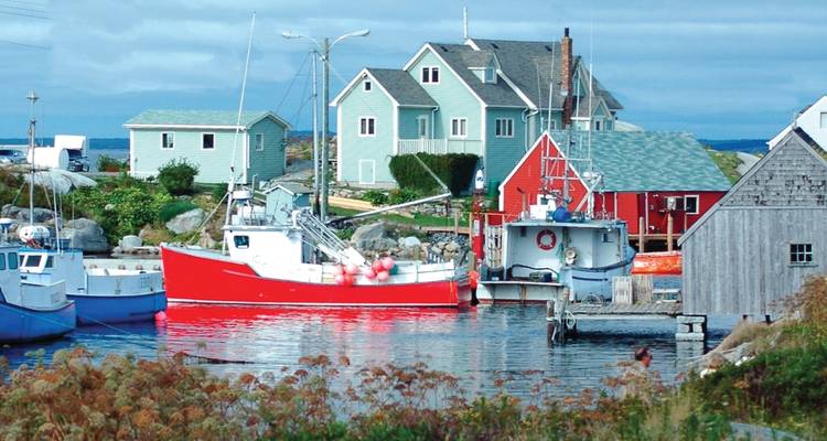 De petits bateaux de pêche et des maisons aux couleurs vives se regroupent autour d'une baie maritime calme en Nouvelle-Écosse.