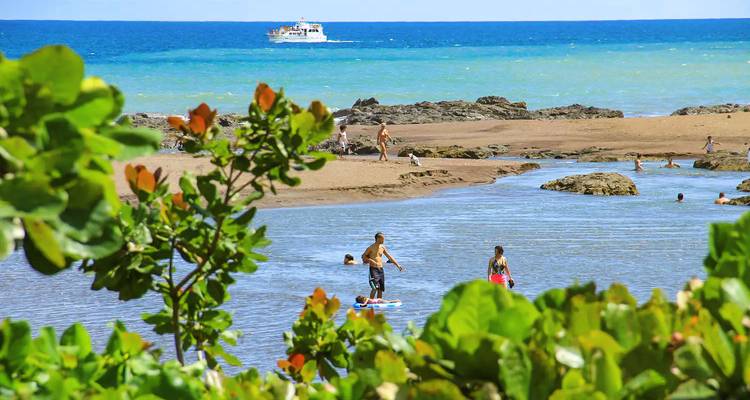Des gens profitant de la plage avec un bateau au loin