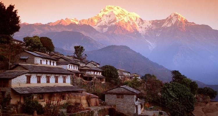 Mountain village with traditional stone houses and snowy peaks.