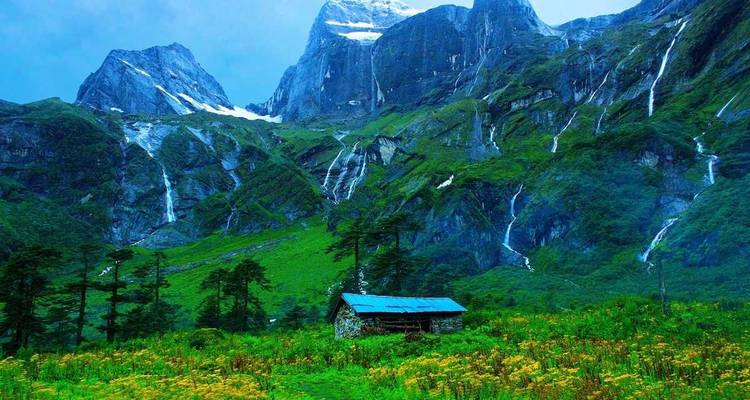 Lush green valley with cascading waterfalls and a lone hut.