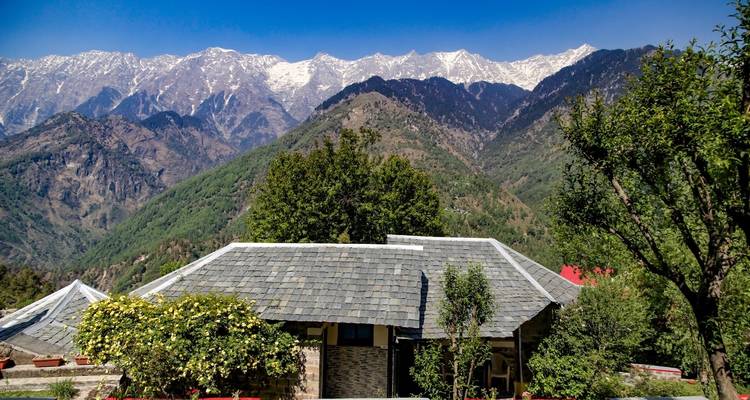 Mountain view with traditional stone house and greenery.