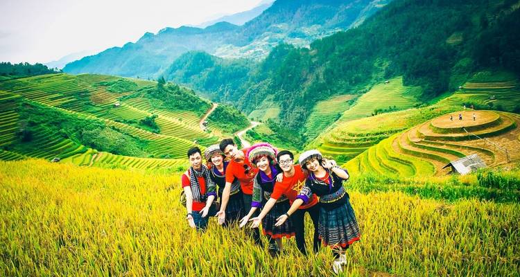 Gruppe von Freunden, die fröhlich vor Reisterrassen posieren.