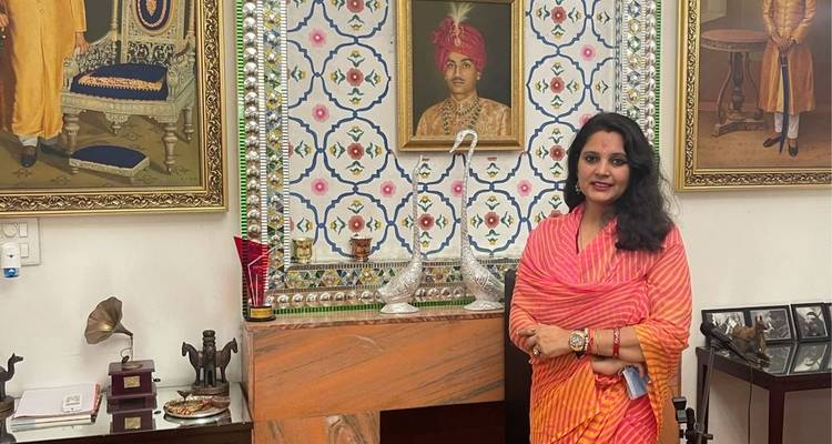 Woman posing in a room decorated with portraits and artifacts.