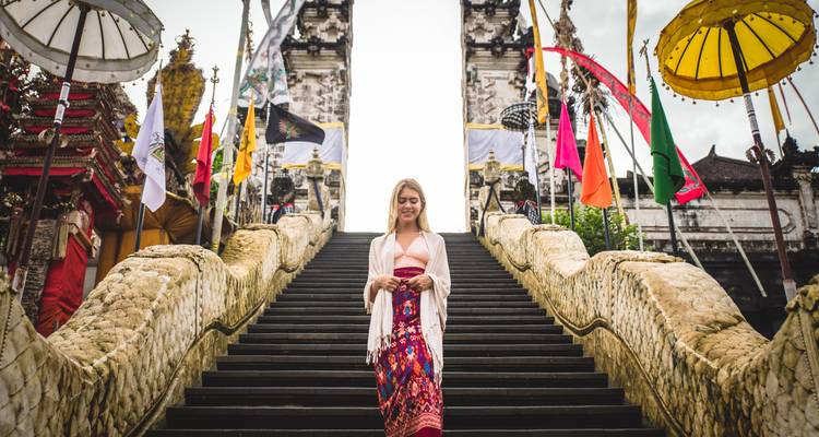 Frau, die eine mit traditionellen Fahnen geschmückte Treppe an einem Tempel hinuntergeht.