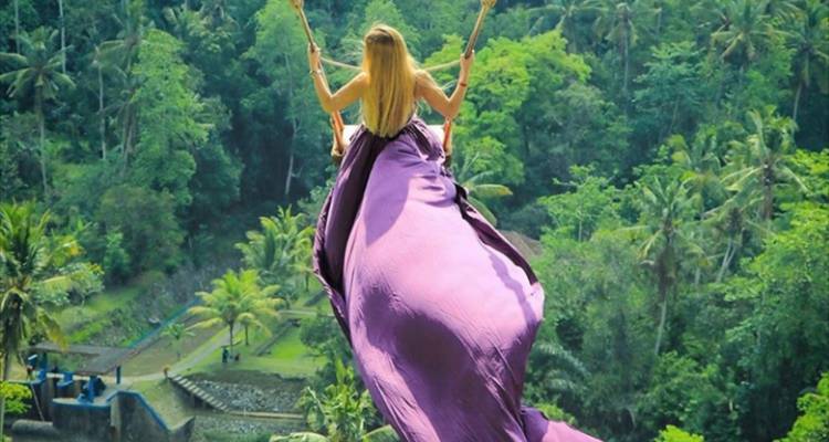 Frau genießt eine Schaukel mit malerischen Reisfeldern und üppigem Grün.