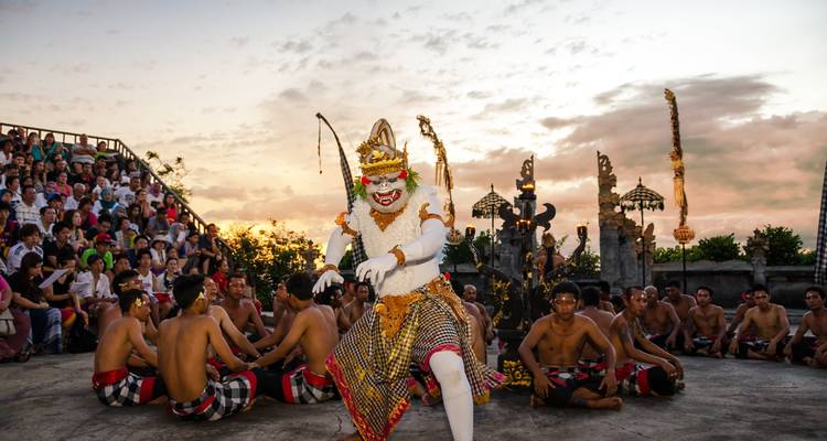 Kulturelle Aufführung mit aufwendig gekleideten Darstellern und Publikum bei Sonnenuntergang.