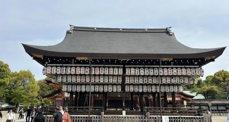 Vista frontal del escenario del Santuario Yasaka en Kioto adornado con filas de linternas blancas y visitantes deambulando abajo.