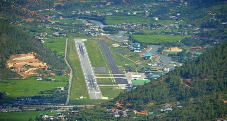Vista aérea de un aeropuerto rodeado de montañas verdes.
