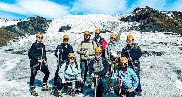 Grupo de aventureros con cascos parados en un glaciar azul brillante con montañas detrás.