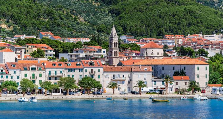 Un pueblo costero histórico con una iglesia y una hilera de barcos en el puerto.