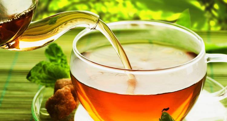 Thee die wordt ingeschonken in een glazen kopje met een frisse, groene achtergrond.