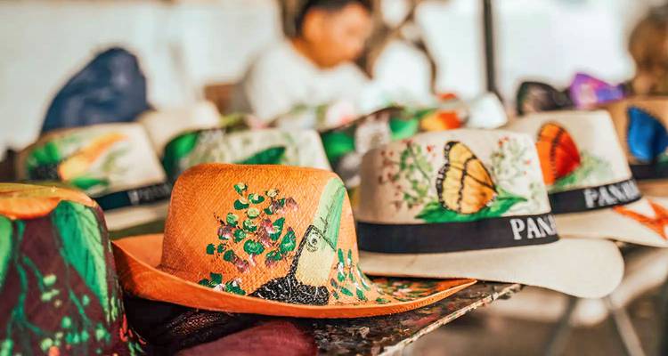 Sombreros coloridos expuestos en un mercado con una persona en el fondo.