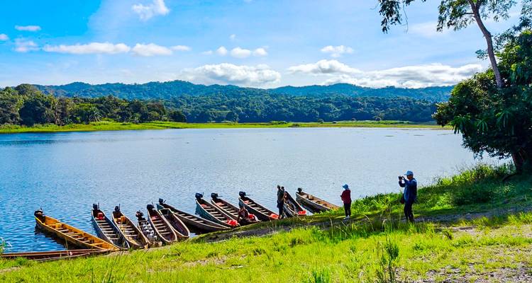 Personas con canoas en la orilla de un río en un paisaje exuberante.