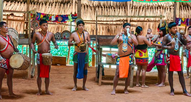 Grupo de personas vestidas con atuendos tradicionales actuando dentro de una cabaña.