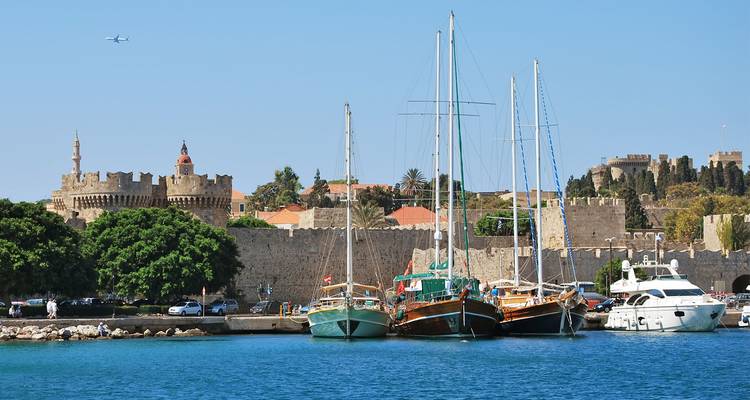 Port de Rhodes avec des voiliers amarrés devant les murs et les tours de pierre médiévaux