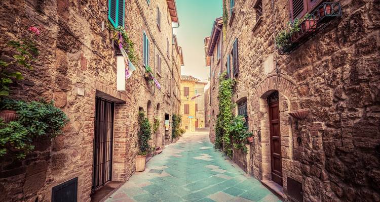 Charmante schmale Straße mit Steingebäuden und Blumen.