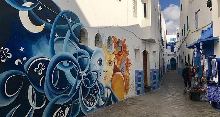 Straatkunstmuurschildering in een smalle steeg met wandelende mensen.