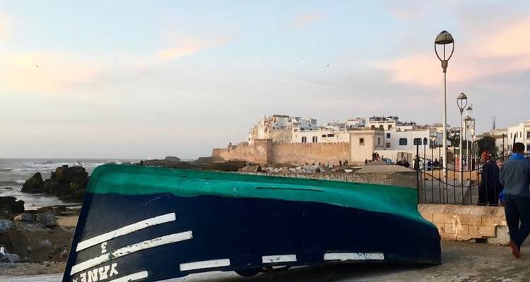 Kustplaats zicht met een boot en verre gebouwen nabij de kust.