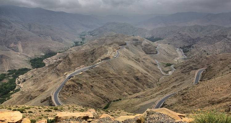 Kronkelende bergweg door droog terrein.