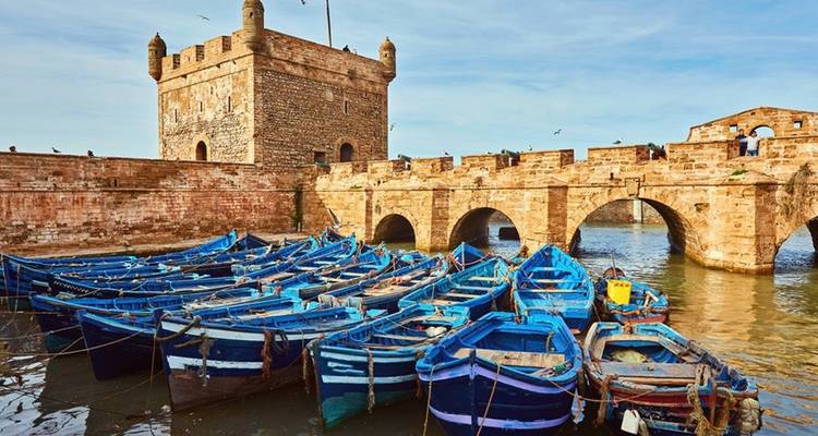 Blauwe vissersboten afgemeerd bij een oud fort.