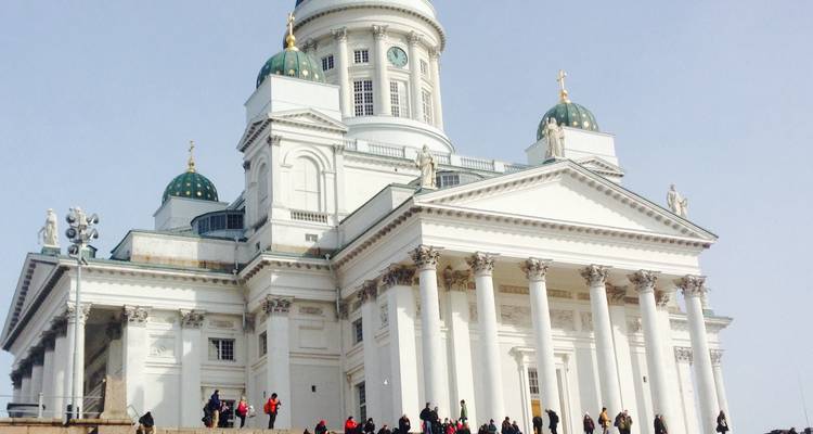 White cathedral with green domes and statues.