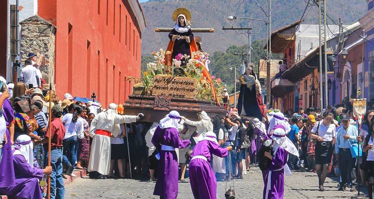 Procession colorée dans la rue avec des gens en tenue traditionnelle.