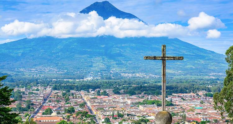 Vue panoramique d'une ville avec une croix surplombant une grande montagne.