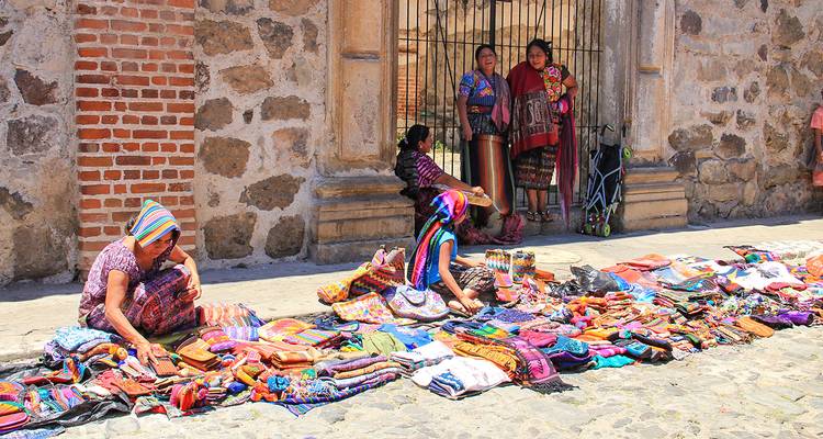 Des femmes vendant des textiles dans une rue pavée.