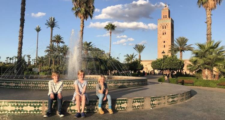 Famille avec fontaine et mosquée en arrière-plan.