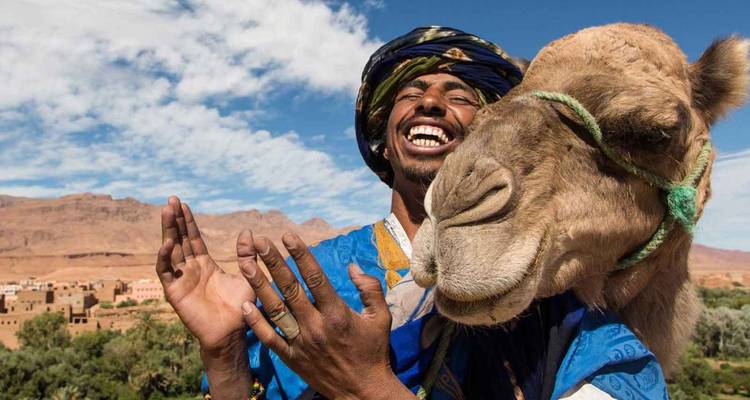 Homme avec un chameau dans un décor désertique.