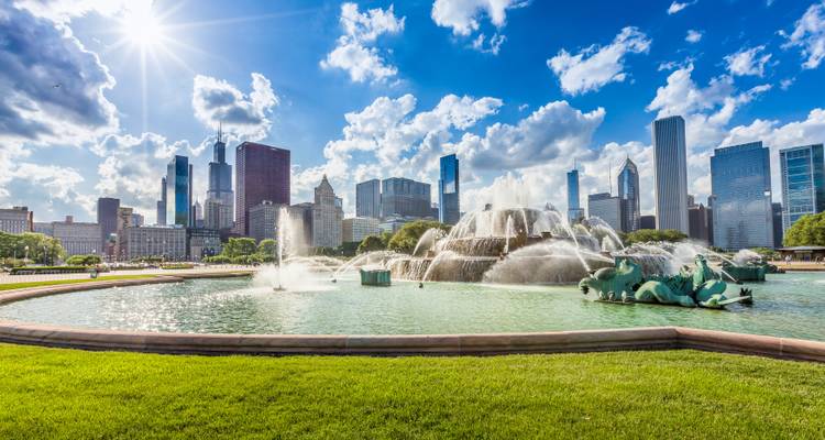 La fontaine Buckingham pulvérisant de l'eau avec la ligne d'horizon de Chicago et un soleil éclatant créant des halos lumineux dans un ciel bleu.
