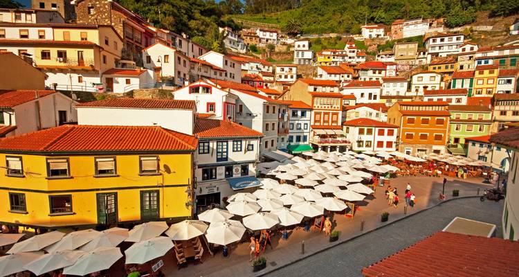 Pueblo colorido en la ladera con muchas sombrillas en una plaza.