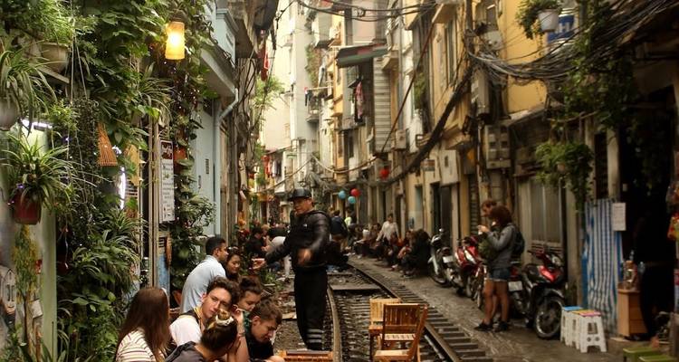 Menschen sitzen auf einer schmalen Straße mit Bahngleisen.
