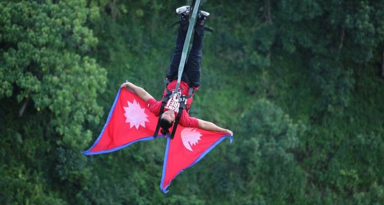 Person bungee jumping upside down with Nepal flags.