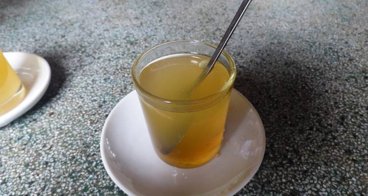 Ein Glas Tee mit einem Löffel auf einer Untertasse.