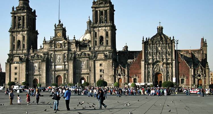 Der historische Metropolitankathedrale dominiert den geschäftigen Zócalo-Platz von Mexiko-Stadt, der von Menschenmengen und Tauben erfüllt ist.