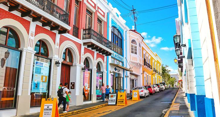 Calle histórica pintada de colores vibrantes con gente caminando.